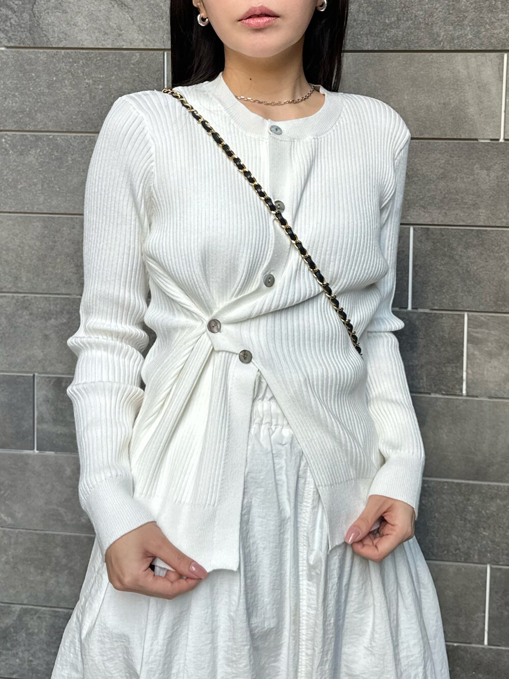 ホワイト系のスカート、ホワイト系のニット/セーター、ブラック系のバッグを着用したレディースの春コーディネートの2枚目の写真