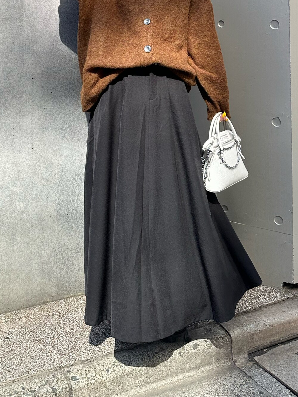 ブラック系のスカート、ホワイト系のショルダーバッグ、ブラウン系のカーディガン/ボレロを着用したレディースの春コーディネートの3枚目の写真