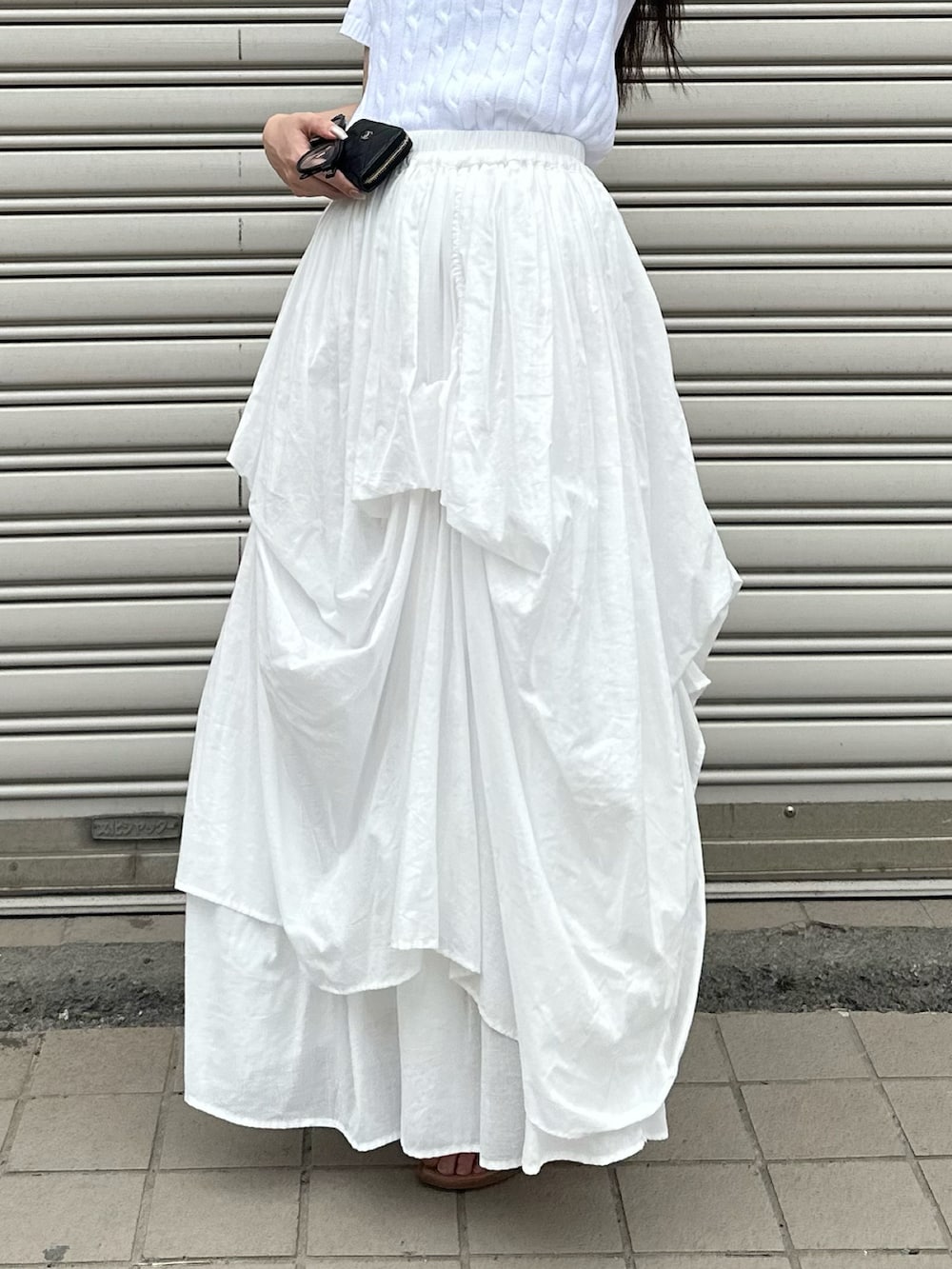 ホワイト系のスカート、ホワイト系のニット/セーター、ベージュ系のサンダルを着用したレディースの春コーディネートの2枚目の写真