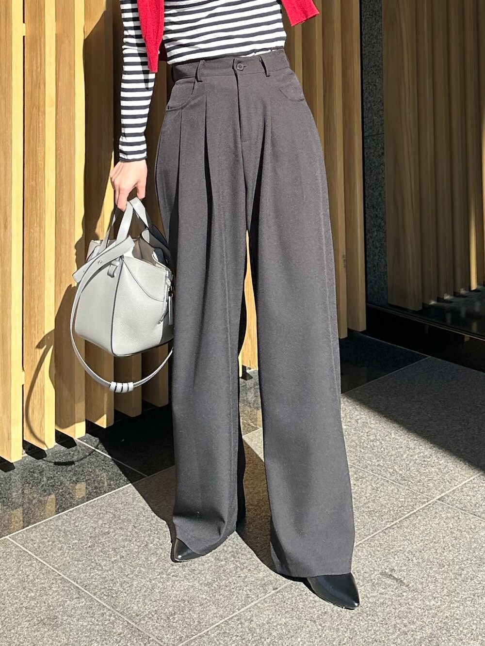 ブラック系のスラックス、グレー系のトートバッグ、レッド系のカーディガン/ボレロを着用したレディースの春コーディネートの3枚目の写真