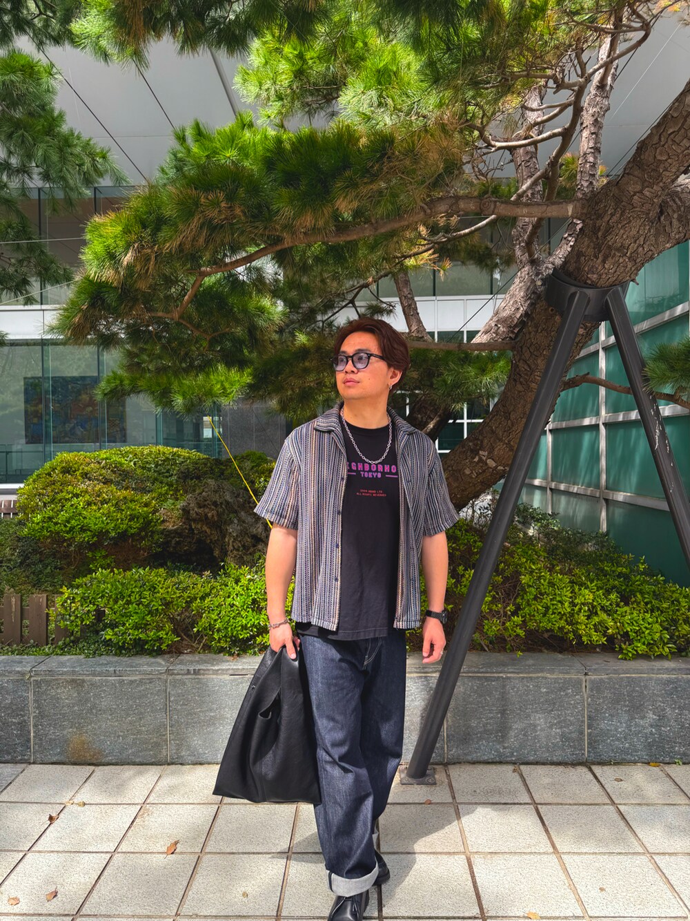 ブルー系のデニムパンツ、ブラック系のシューズ、ブラック系のクラッチバッグを着用したメンズの春コーディネートの2枚目の写真