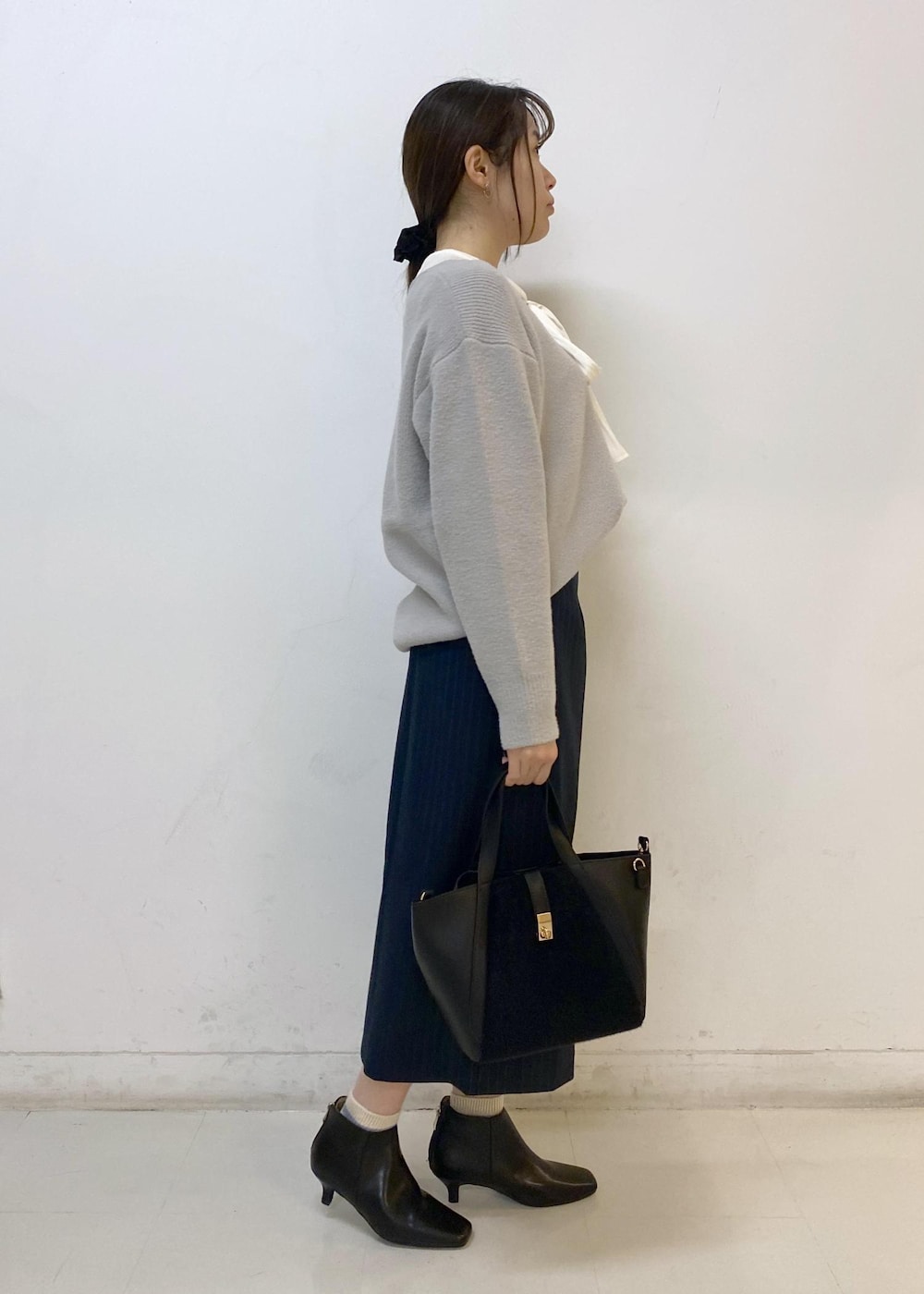 ブルー系のスカート、グレー系のニット/セーター、ホワイト系のシャツ/ブラウスを着用したレディースの秋コーディネートの3枚目の写真