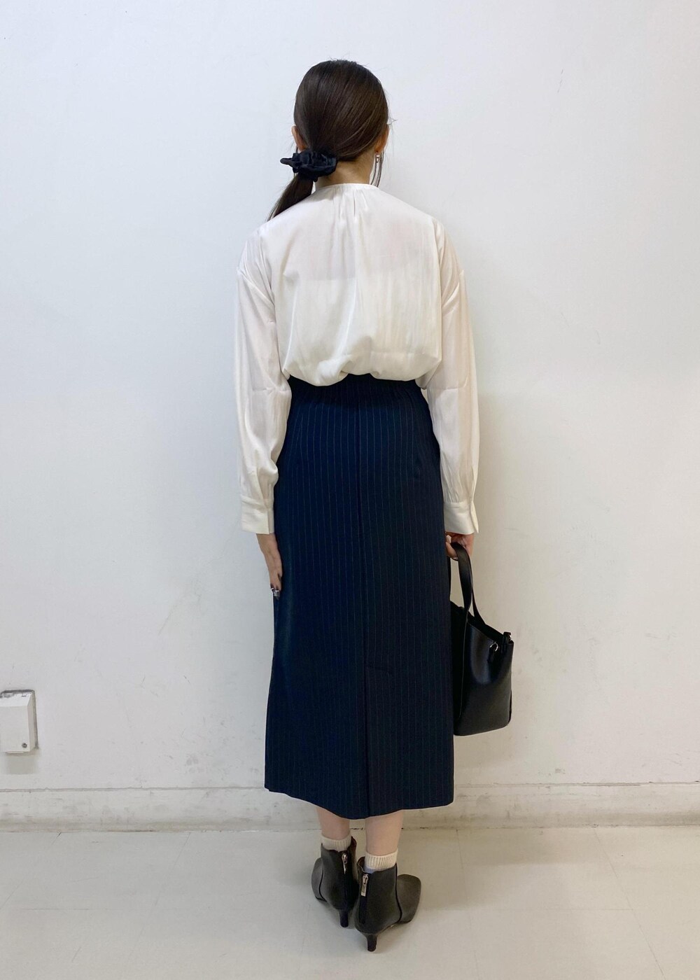 ブルー系のスカート、グレー系のニット/セーター、ホワイト系のシャツ/ブラウスを着用したレディースの秋コーディネートの8枚目の写真