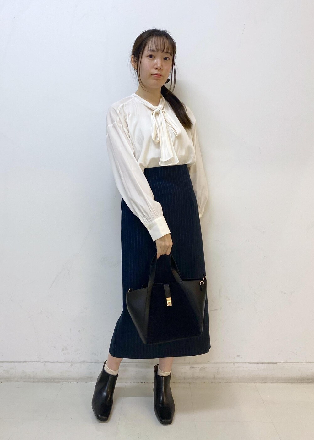 ブルー系のスカート、グレー系のニット/セーター、ホワイト系のシャツ/ブラウスを着用したレディースの秋コーディネートの6枚目の写真