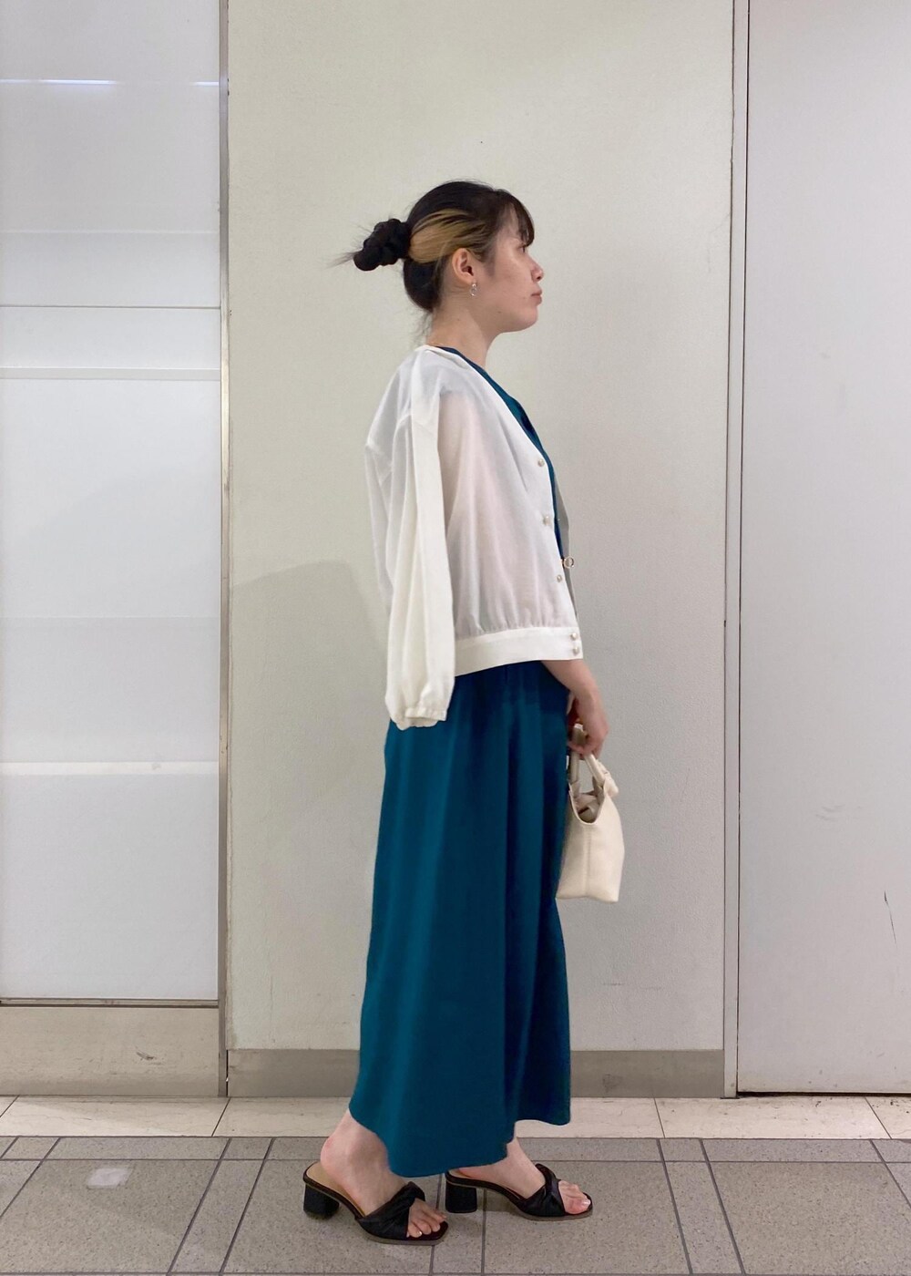 ブラック系のサンダル、ホワイト系のショルダーバッグ、グリーン系のワンピースを着用したレディースの夏コーディネートの3枚目の写真