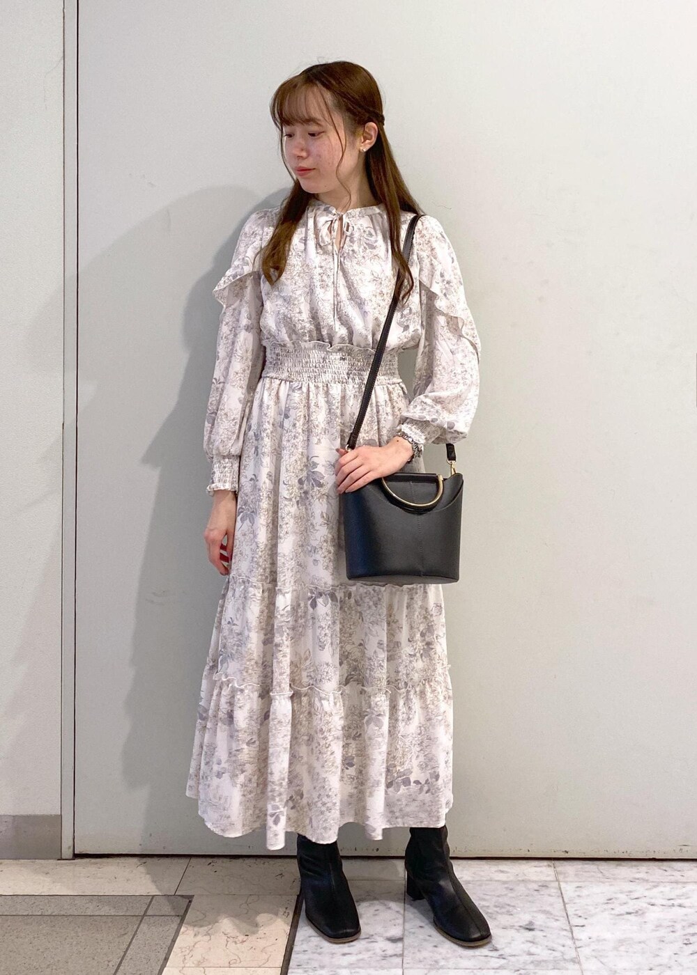 ホワイト系のワンピース、ブラック系のカーディガン/ボレロ、ブラック系のブーツを着用したレディースの冬コーディネートの5枚目の写真