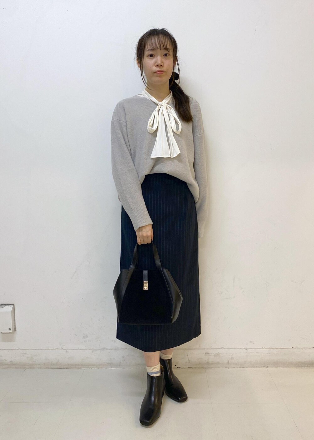 ブルー系のスカート、グレー系のニット/セーター、ホワイト系のシャツ/ブラウスを着用したレディースの秋コーディネートの2枚目の写真