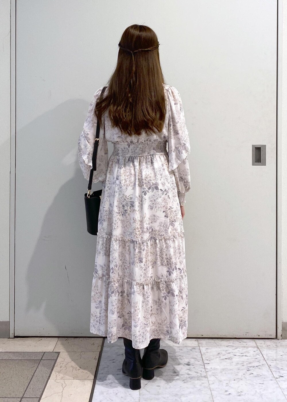 ホワイト系のワンピース、ブラック系のカーディガン/ボレロ、ブラック系のブーツを着用したレディースの冬コーディネートの7枚目の写真