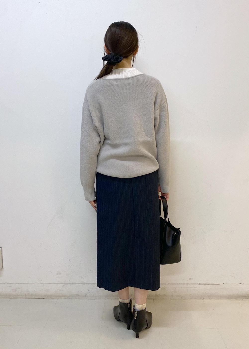 ブルー系のスカート、グレー系のニット/セーター、ホワイト系のシャツ/ブラウスを着用したレディースの秋コーディネートの4枚目の写真