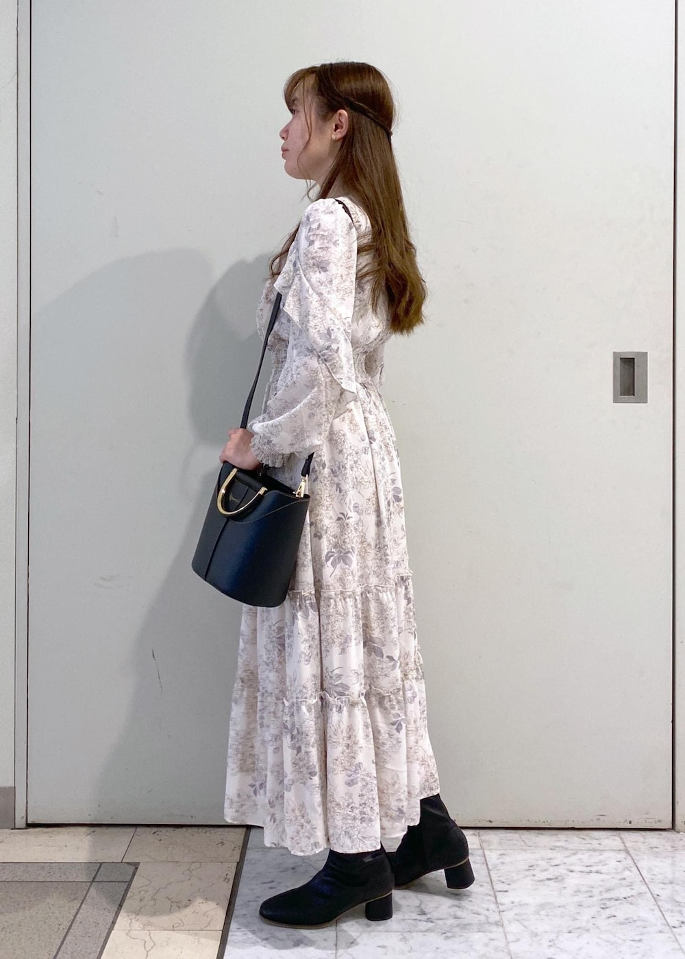 ホワイト系のワンピース、ブラック系のカーディガン/ボレロ、ブラック系のブーツを着用したレディースの冬コーディネートの6枚目の写真