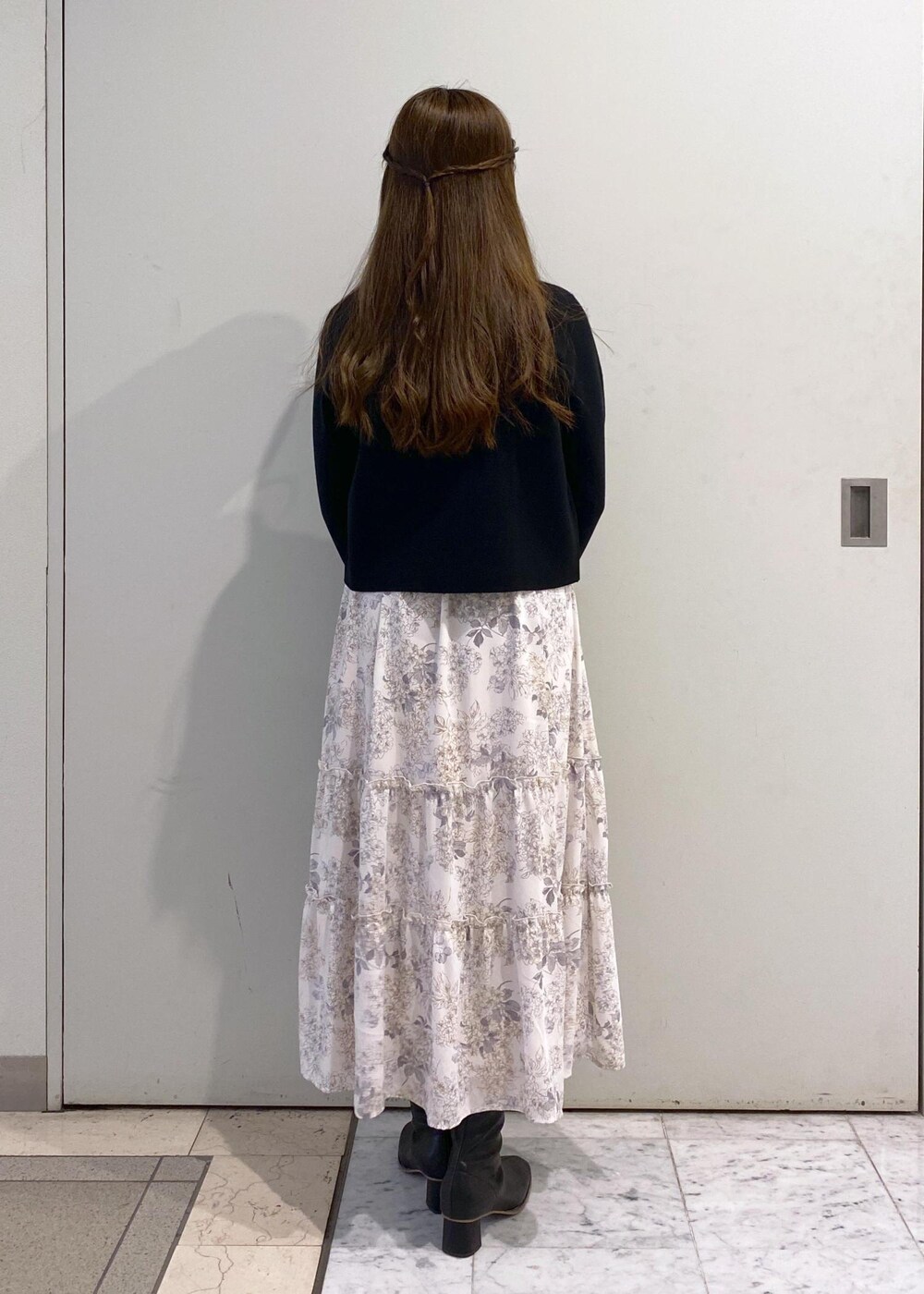 ホワイト系のワンピース、ブラック系のカーディガン/ボレロ、ブラック系のブーツを着用したレディースの冬コーディネートの4枚目の写真