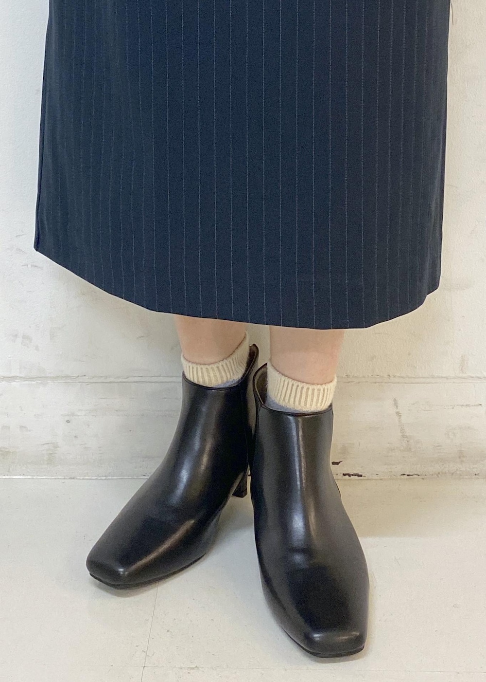 ブルー系のスカート、グレー系のニット/セーター、ホワイト系のシャツ/ブラウスを着用したレディースの秋コーディネートの10枚目の写真