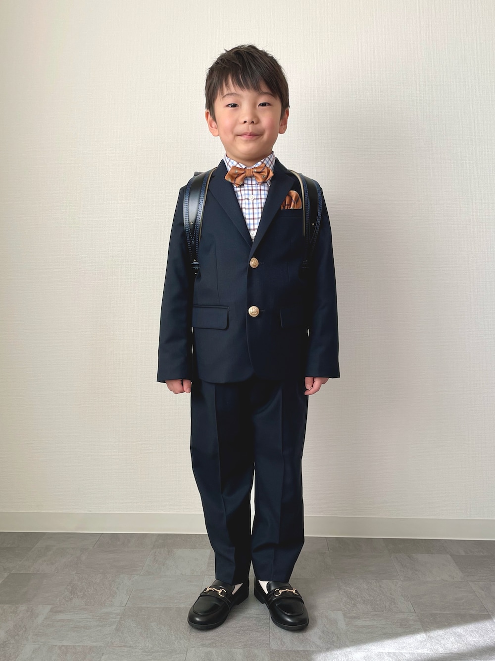 オレンジ系の蝶ネクタイ、ブルー系のシャツ/ブラウス、ブルー系のスーツジャケットを着用したキッズの春コーディネートの2枚目の写真