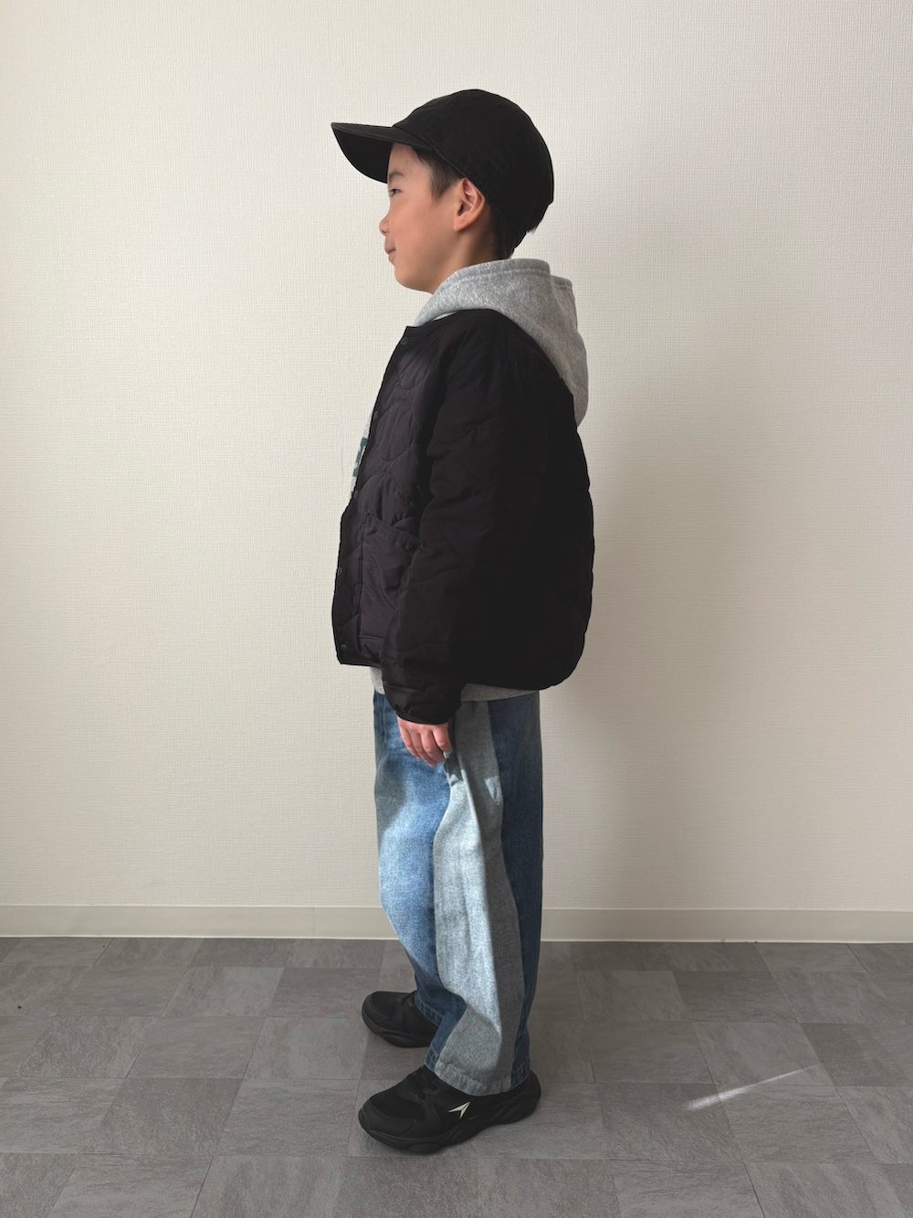 グレー系のパーカー、ブラック系のブルゾン、ブルー系のデニムパンツを着用したキッズの冬コーディネートの2枚目の写真