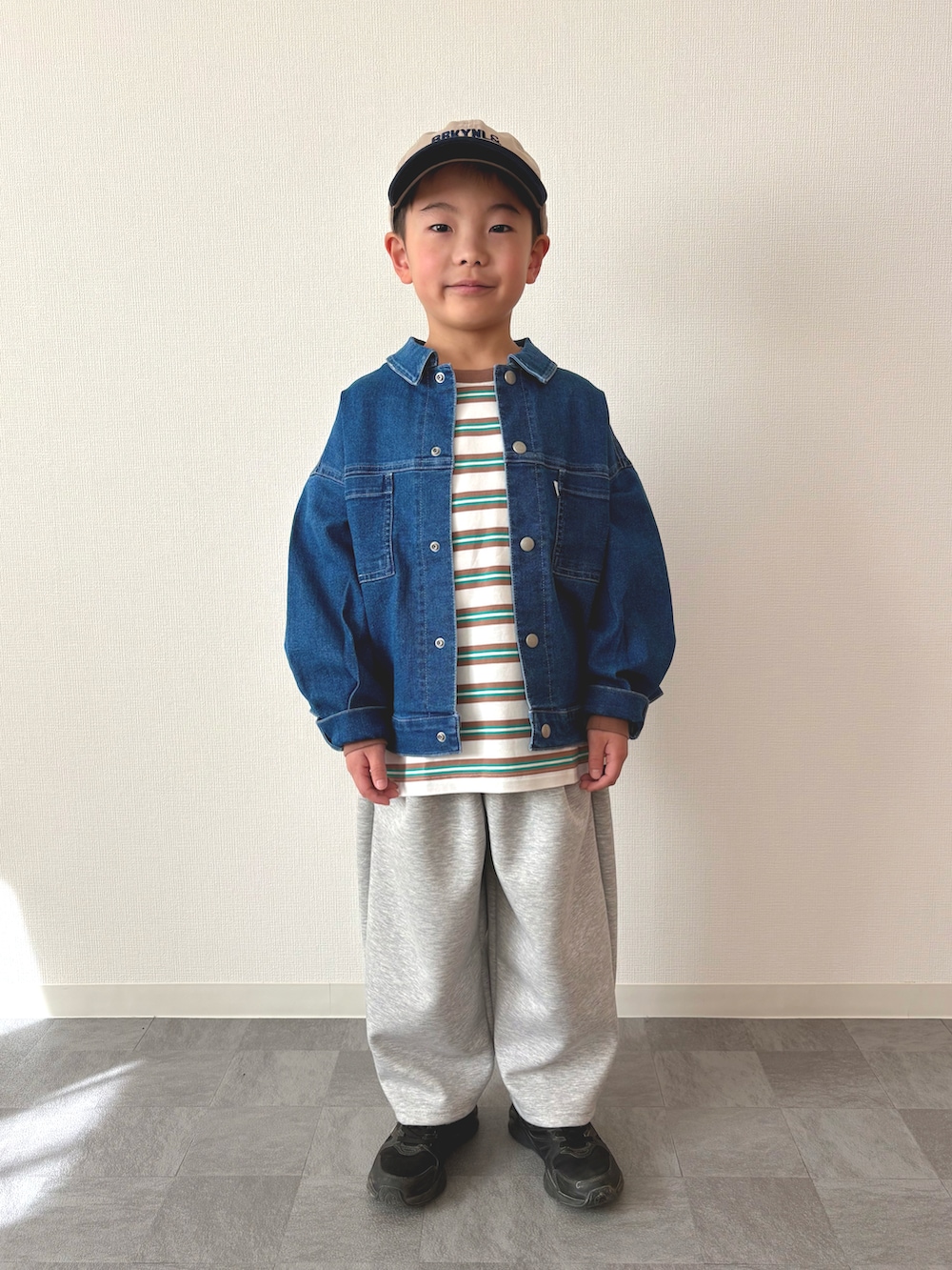 ブラック系のスニーカー、グリーン系のTシャツ/カットソー、ブルー系のデニムジャケットを着用したキッズの春コーディネートの4枚目の写真