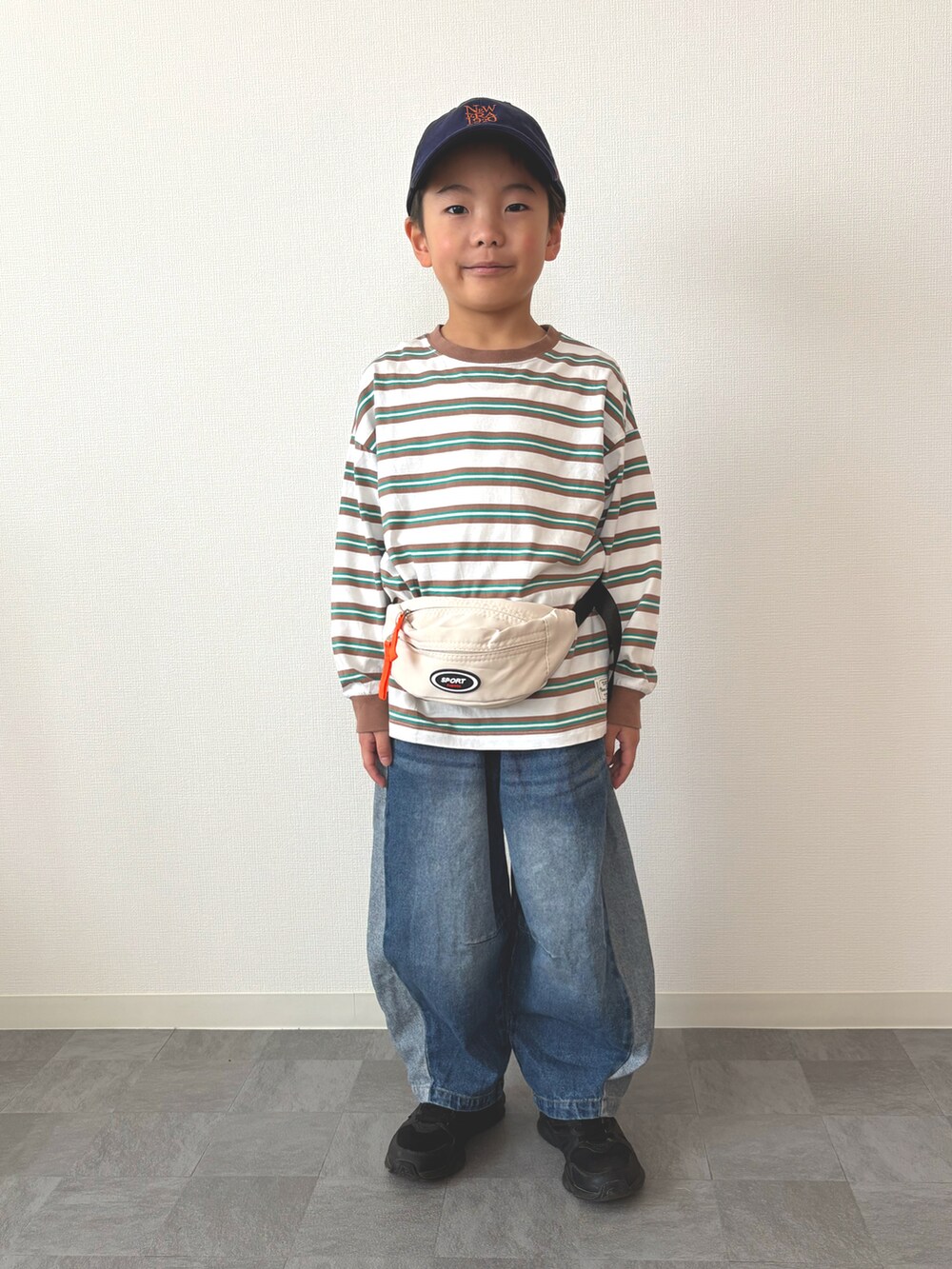 グリーン系のTシャツ/カットソー、ホワイト系のボディバッグ/ウエストポーチ、ブルー系のデニムパンツを着用したキッズの春コーディネートの4枚目の写真