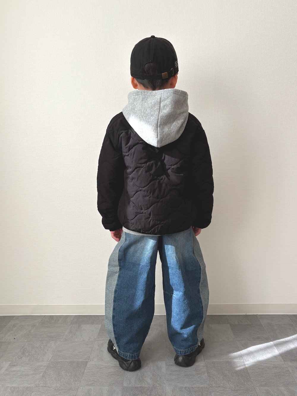 グレー系のパーカー、ブラック系のブルゾン、ブルー系のデニムパンツを着用したキッズの冬コーディネートの3枚目の写真