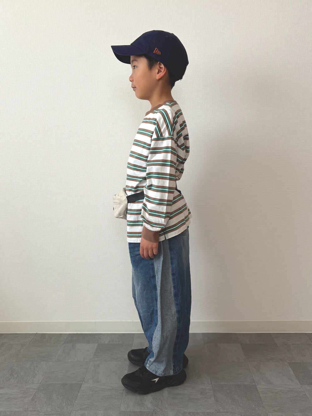 グリーン系のTシャツ/カットソー、ホワイト系のボディバッグ/ウエストポーチ、ブルー系のデニムパンツを着用したキッズの春コーディネートの2枚目の写真