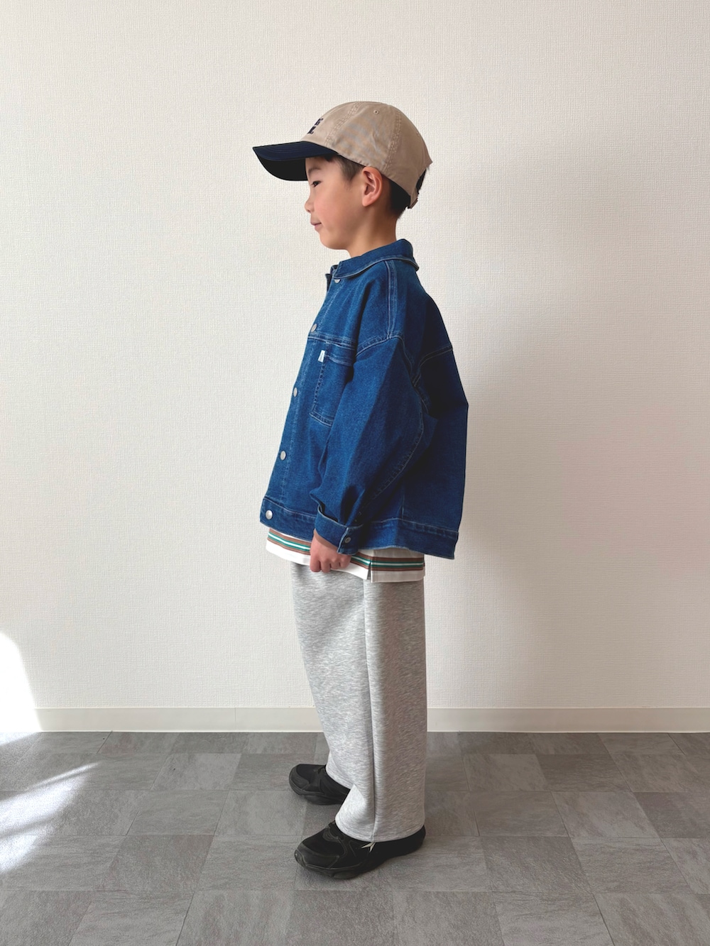 ブラック系のスニーカー、グリーン系のTシャツ/カットソー、ブルー系のデニムジャケットを着用したキッズの春コーディネートの2枚目の写真