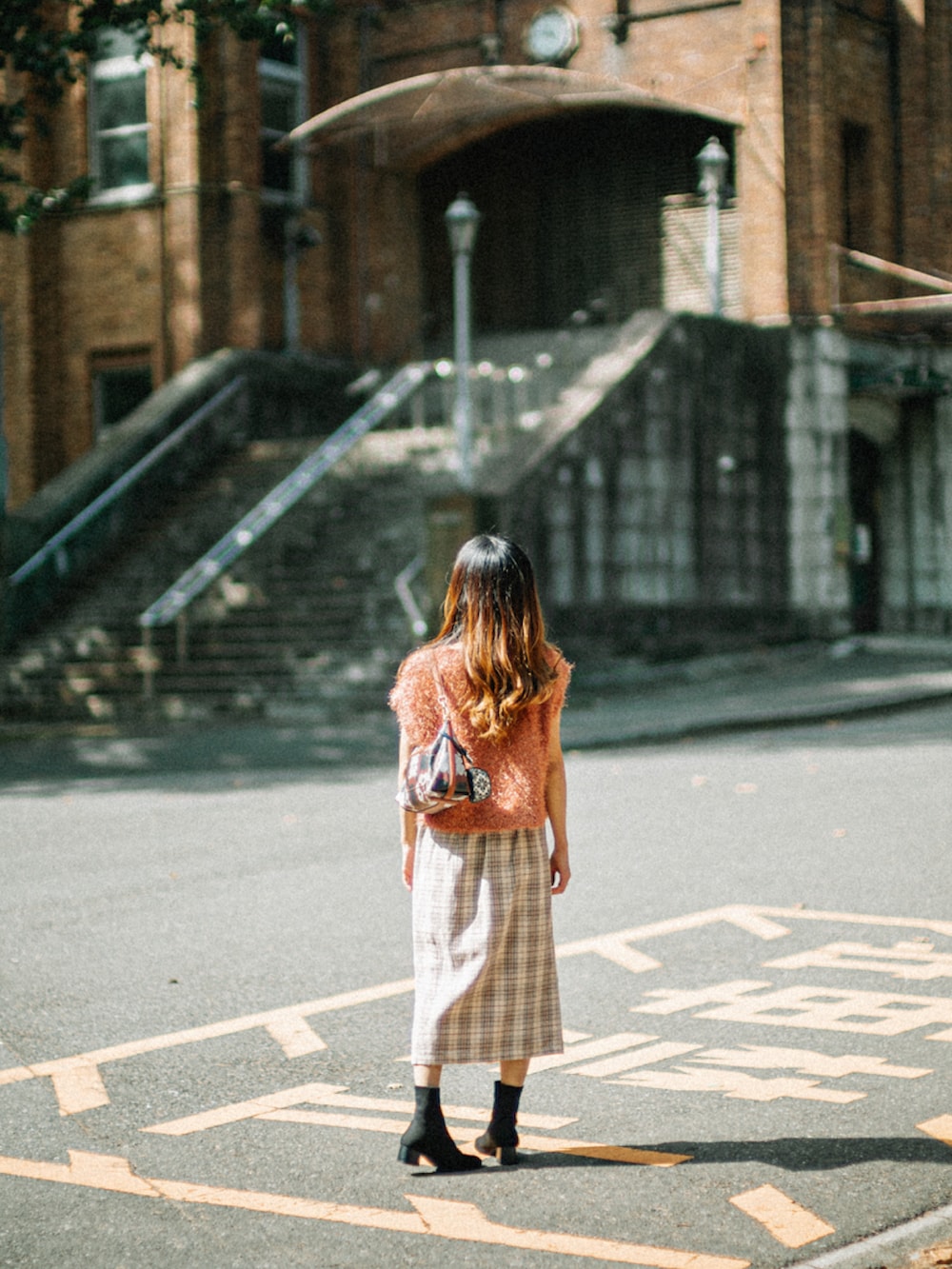 オレンジ系のニット/セーター、ブラウン系のショルダーバッグ、ホワイト系のスカートを着用したレディースの秋コーディネートの3枚目の写真