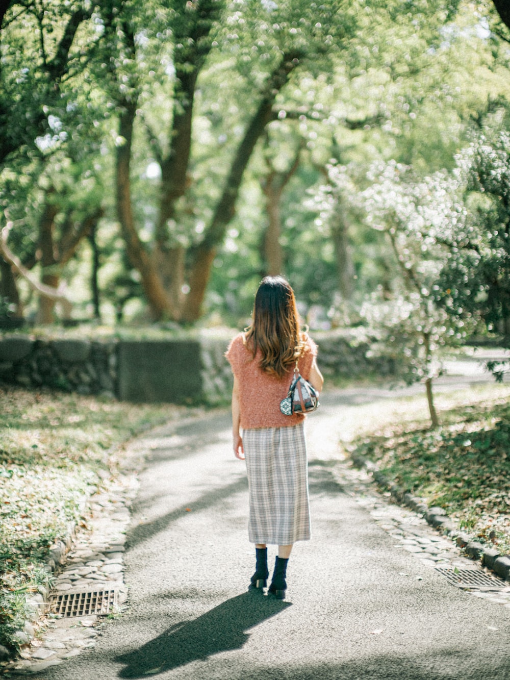 オレンジ系のニット/セーター、ブラウン系のショルダーバッグ、ホワイト系のスカートを着用したレディースの秋コーディネートの5枚目の写真