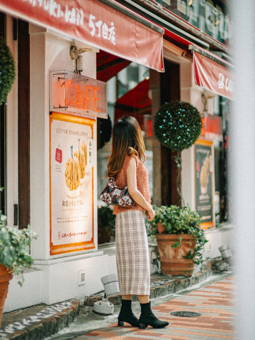 オレンジ系のニット/セーター、ブラウン系のショルダーバッグ、ホワイト系のスカートを着用したレディースの秋コーディネートの2枚目の写真