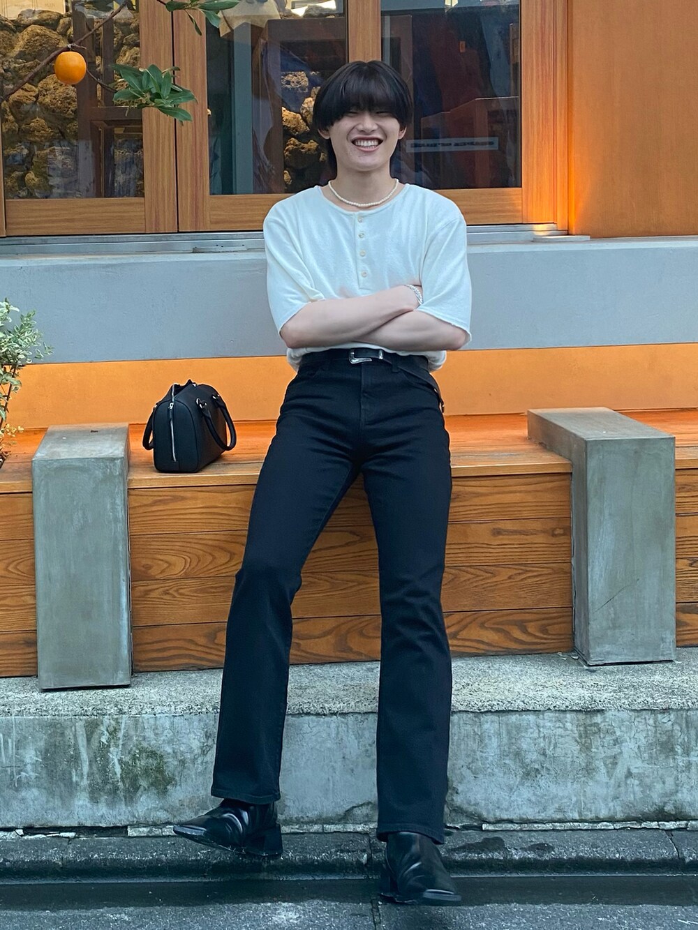 ブラック系のデニムパンツ、ベージュ系のTシャツ/カットソー、ブラック系のブーツを着用したメンズの夏コーディネートの3枚目の写真