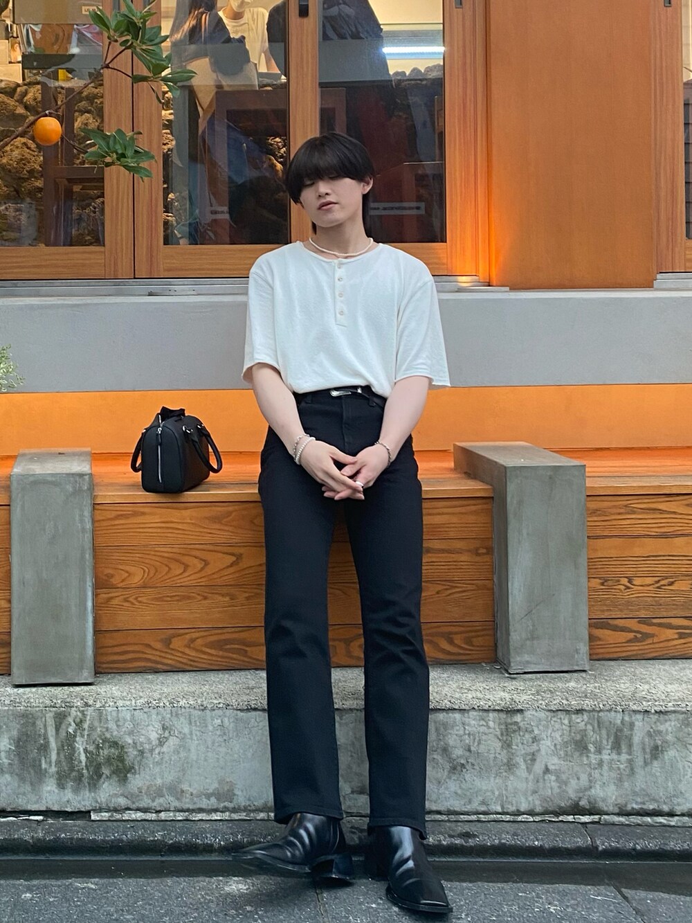 ブラック系のデニムパンツ、ベージュ系のTシャツ/カットソー、ブラック系のブーツを着用したメンズの夏コーディネートの2枚目の写真