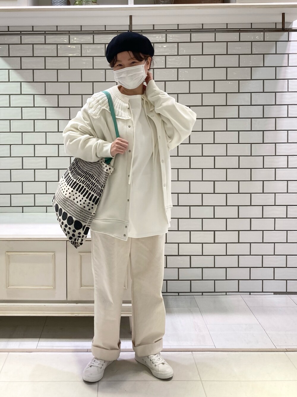 ホワイト系のスニーカー、グリーン系のトートバッグ、ホワイト系のTシャツ/カットソーを着用したレディースの冬コーディネートの2枚目の写真