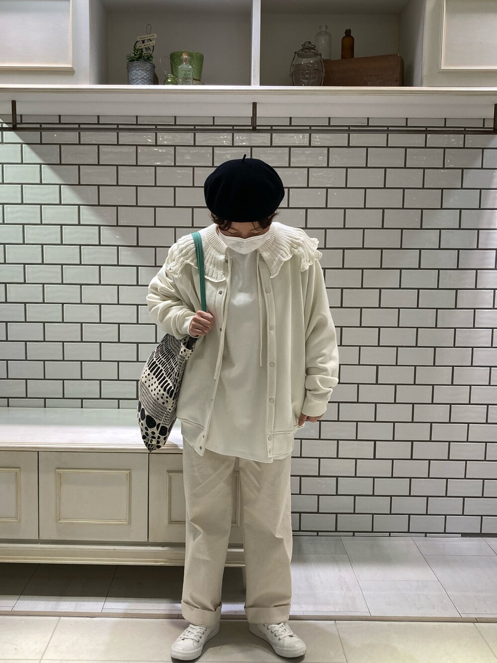 ホワイト系のスニーカー、グリーン系のトートバッグ、ホワイト系のTシャツ/カットソーを着用したレディースの冬コーディネートの3枚目の写真