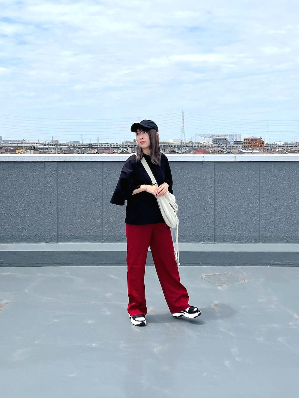 ブラック系のTシャツ/カットソー、ホワイト系のショルダーバッグ、レッド系のパンツを着用したレディースの春コーディネートの2枚目の写真