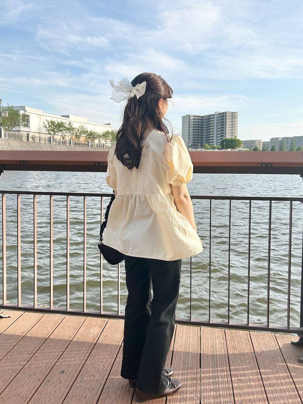 ブラック系のハンドバッグ、ブラック系のデニムパンツを着用したレディースの春コーディネートの2枚目の写真