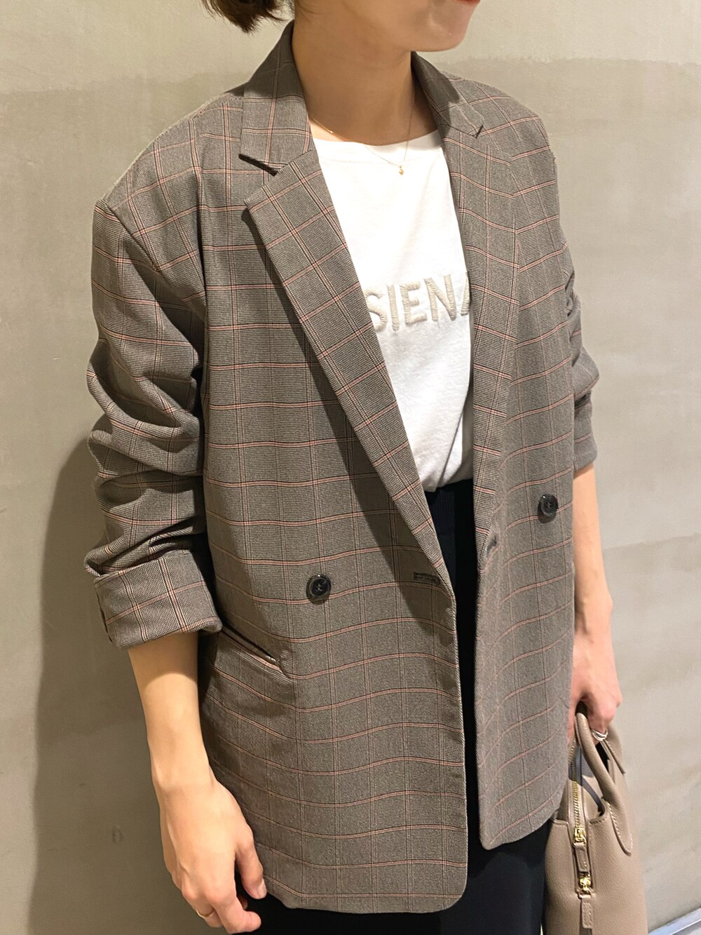 ブラック系のスカート、ブラック系のブーツ、ベージュ系のTシャツ/カットソーを着用したレディースの秋コーディネートの4枚目の写真