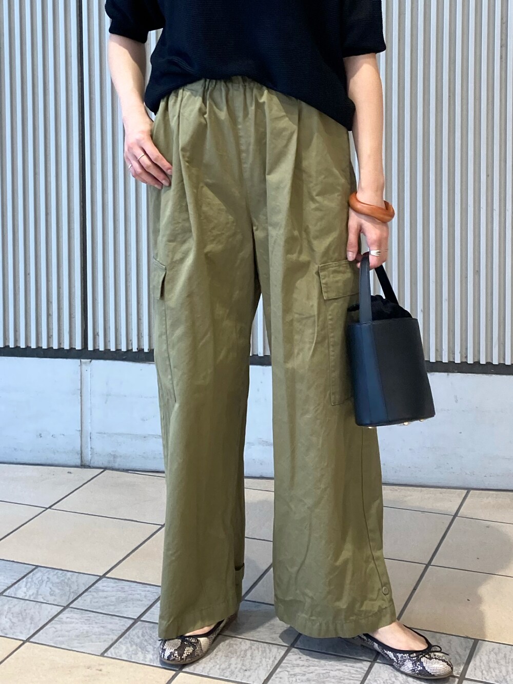 ブラック系のニット/セーター、グリーン系のその他パンツ、ブラック系のショルダーバッグを着用したレディースの夏コーディネートの4枚目の写真