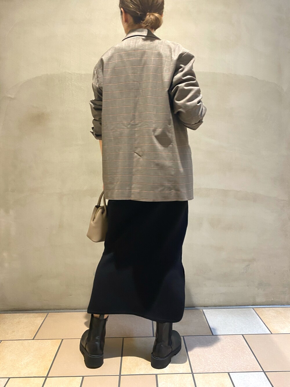 ブラック系のスカート、ブラック系のブーツ、ベージュ系のTシャツ/カットソーを着用したレディースの秋コーディネートの3枚目の写真