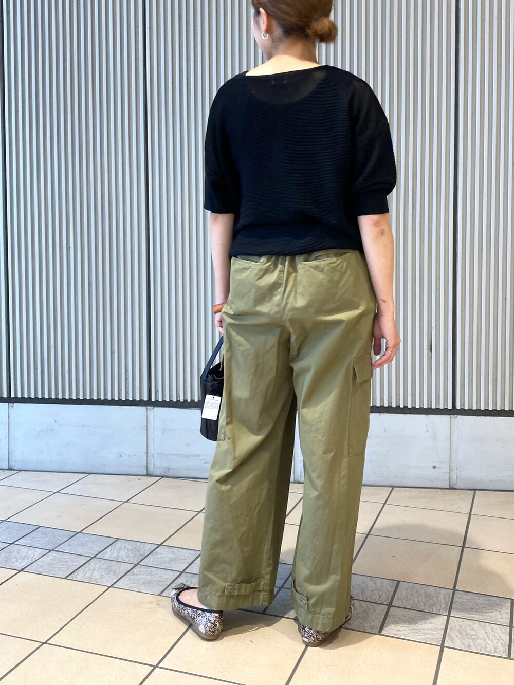 ブラック系のニット/セーター、グリーン系のその他パンツ、ブラック系のショルダーバッグを着用したレディースの夏コーディネートの3枚目の写真