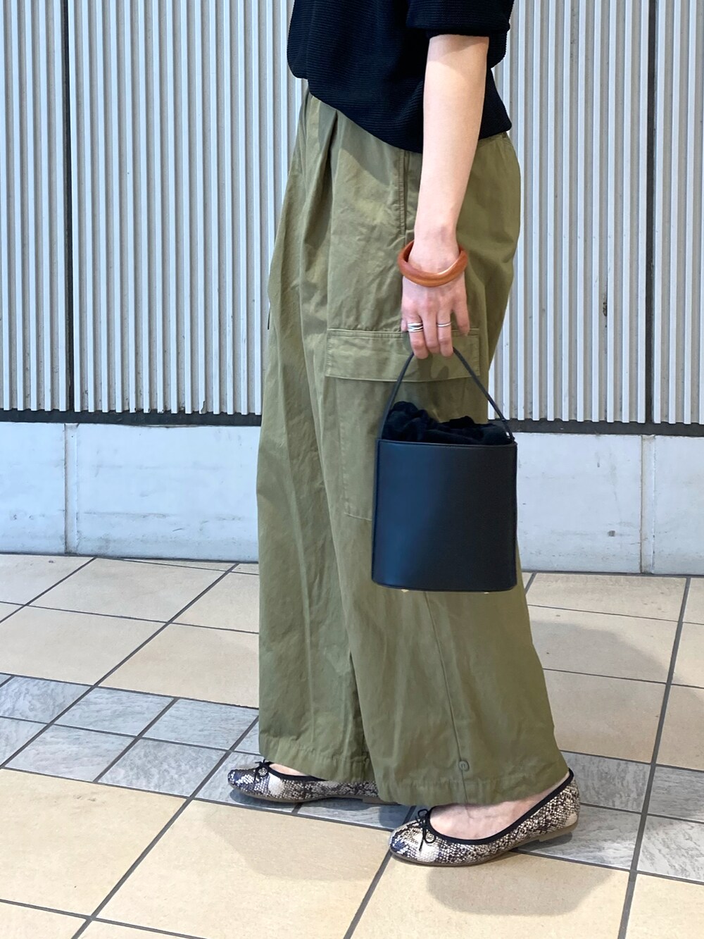 ブラック系のニット/セーター、グリーン系のその他パンツ、ブラック系のショルダーバッグを着用したレディースの夏コーディネートの2枚目の写真