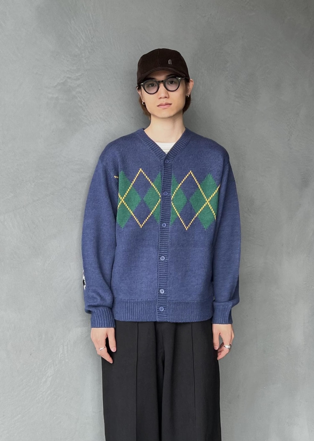 ブラック系のその他パンツ、ブルー系のカーディガン/ボレロ、ブラウン系のキャップを着用したメンズの秋コーディネートの2枚目の写真