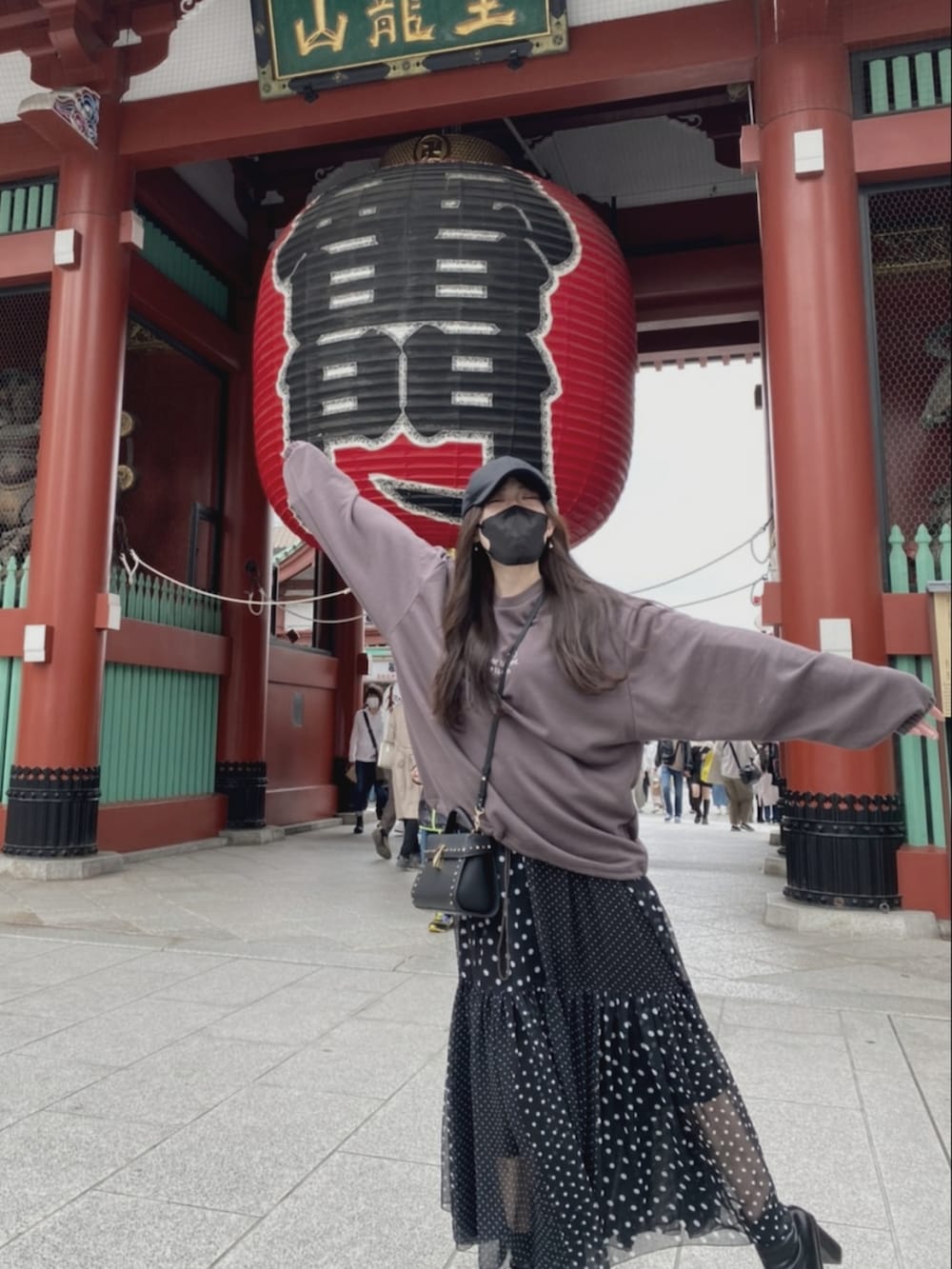 ブラック系のワンピース、ブラウン系のスウェット、ブラック系のショルダーバッグを着用したレディースの春コーディネートの2枚目の写真