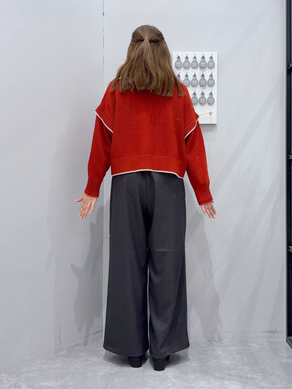 レッド系のニット/セーター、グレー系のその他パンツ、ブラック系のブーツを着用したレディースの秋コーディネートの3枚目の写真