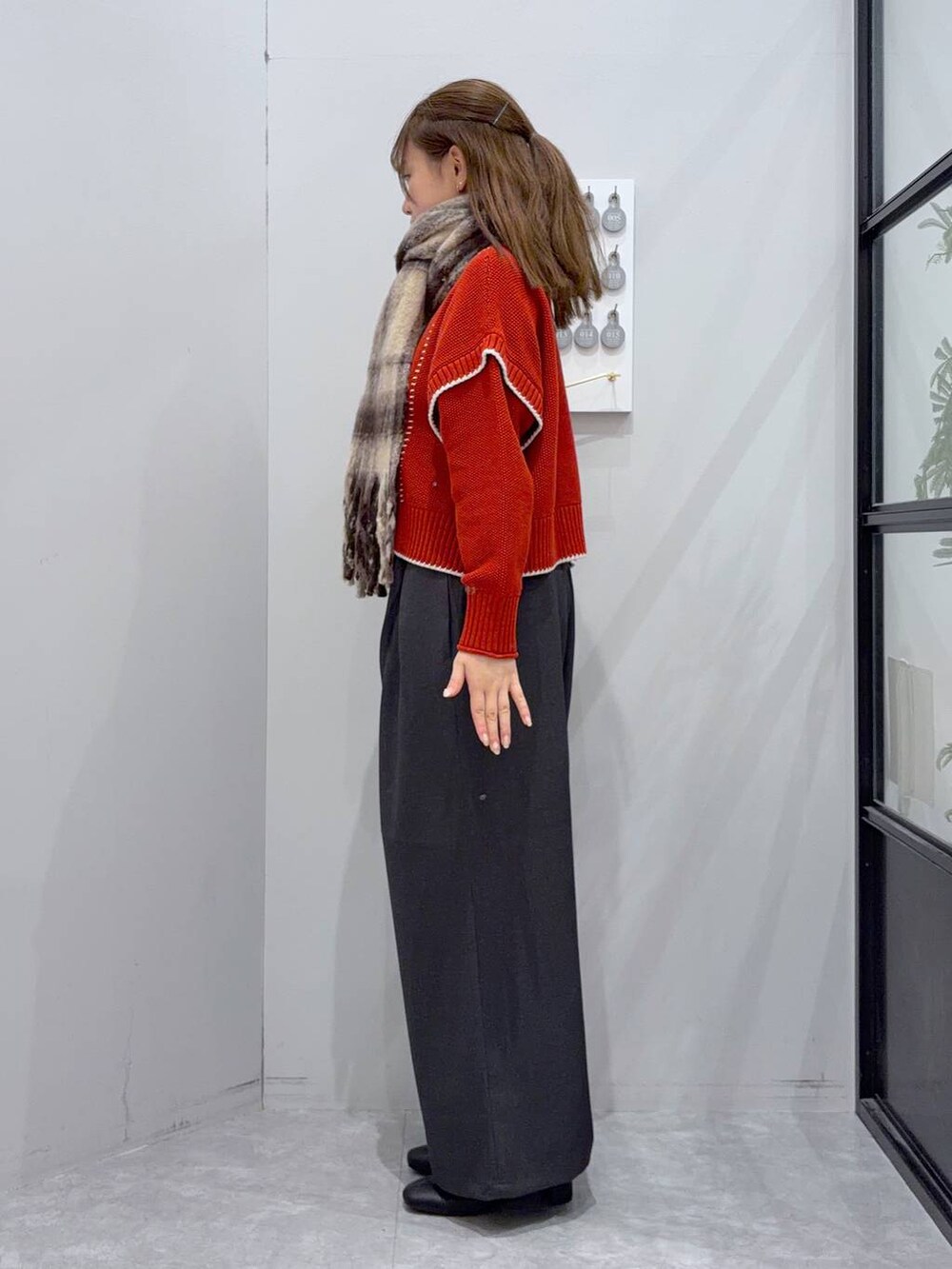 レッド系のニット/セーター、グレー系のその他パンツ、ブラック系のブーツを着用したレディースの秋コーディネートの2枚目の写真