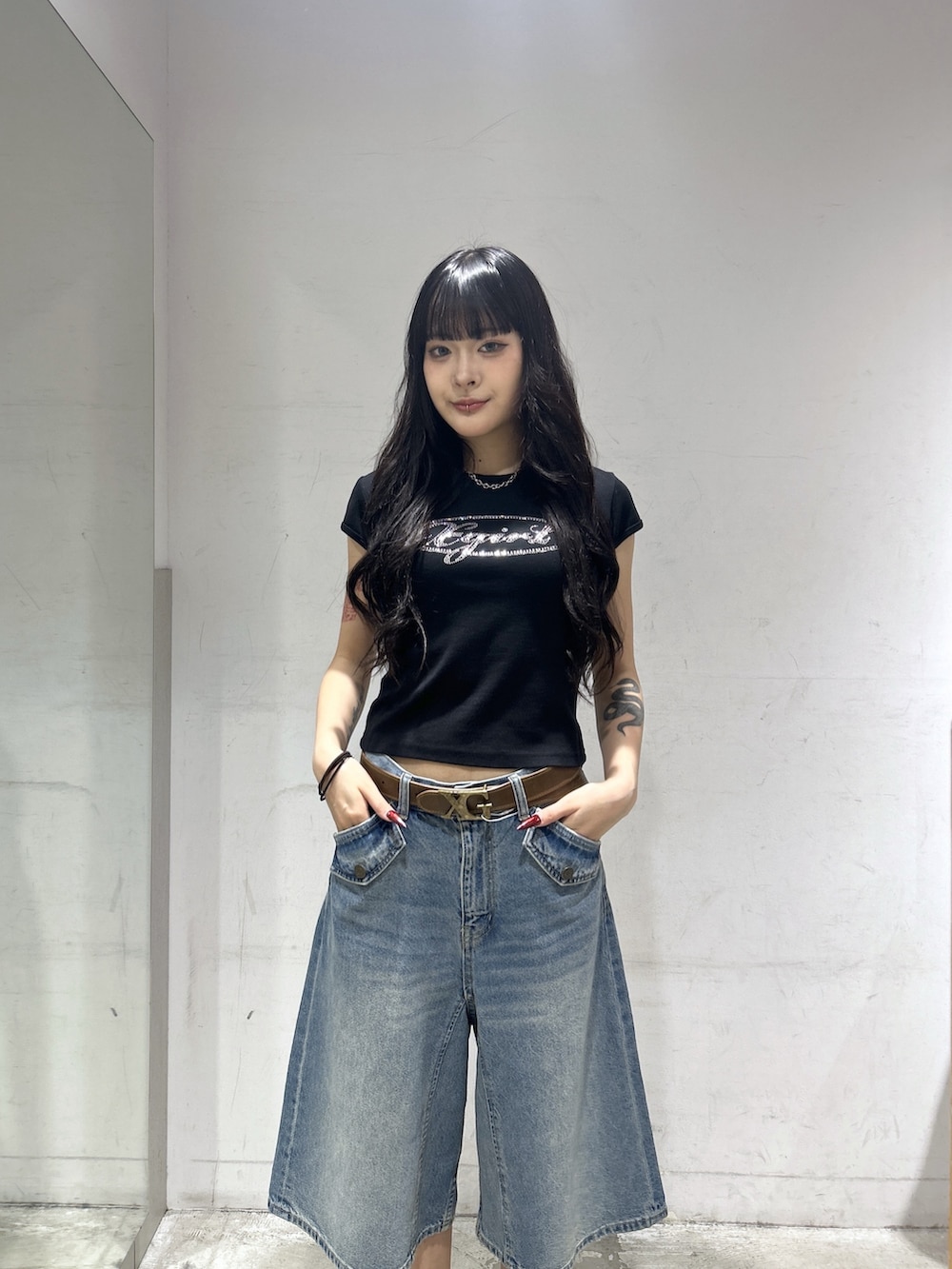 ブルー系のデニムパンツ、オレンジ系のパーカー、ブラック系のTシャツ/カットソーを着用したレディースの春コーディネートの6枚目の写真