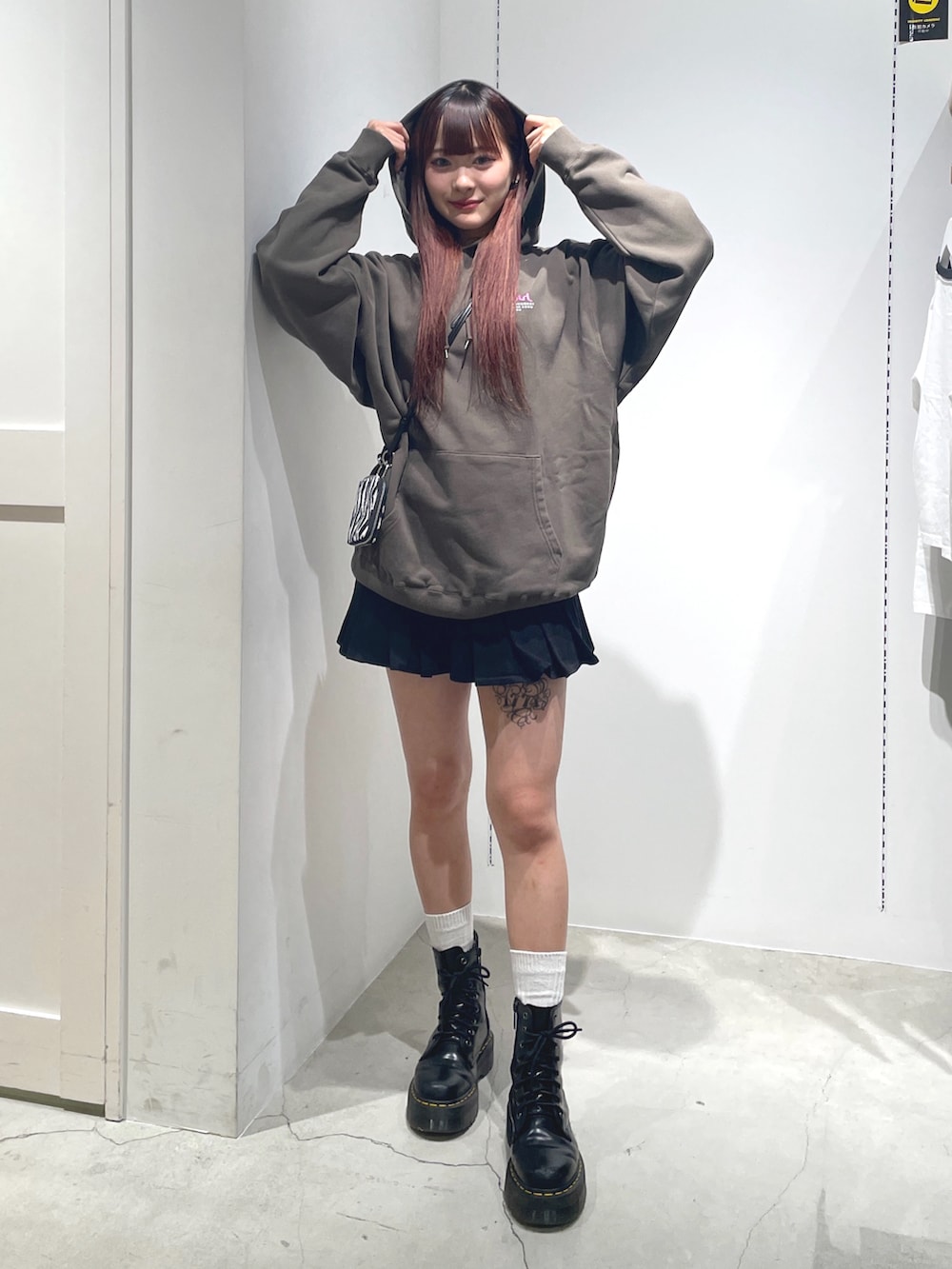 グリーン系のパーカー、ブラック系のスカート、ホワイト系のコインケースを着用したレディースの秋コーディネートの2枚目の写真