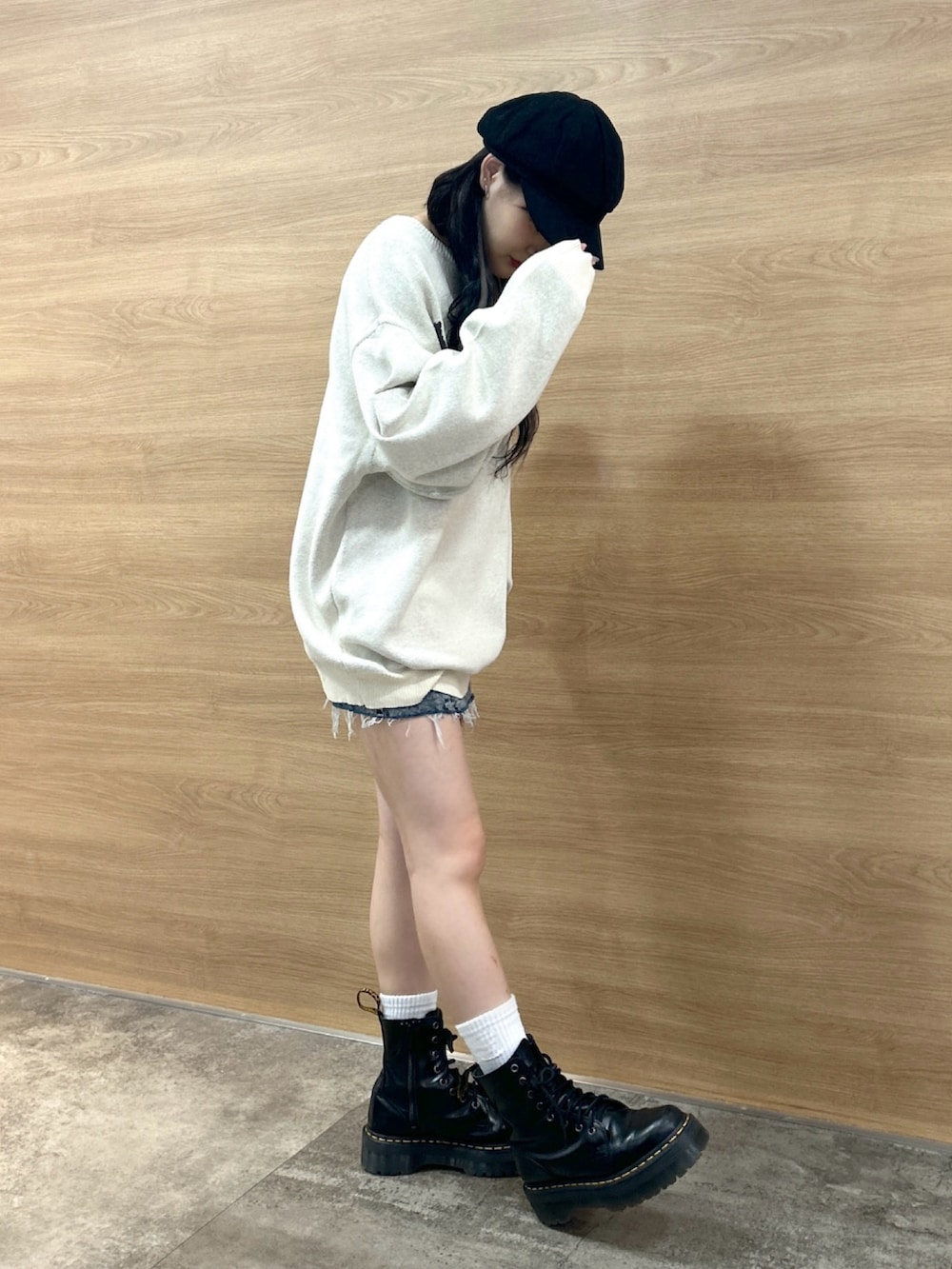 ホワイト系のニット/セーター、ブルー系のデニムスカート、ブラック系のキャスケットを着用したレディースの秋コーディネートの2枚目の写真