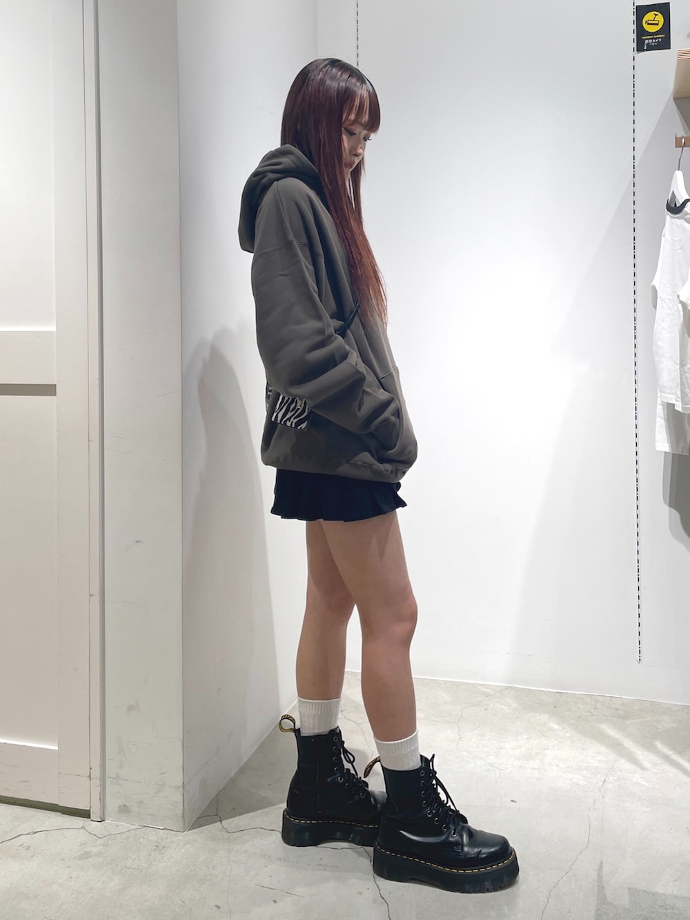 グリーン系のパーカー、ブラック系のスカート、ホワイト系のコインケースを着用したレディースの秋コーディネートの3枚目の写真