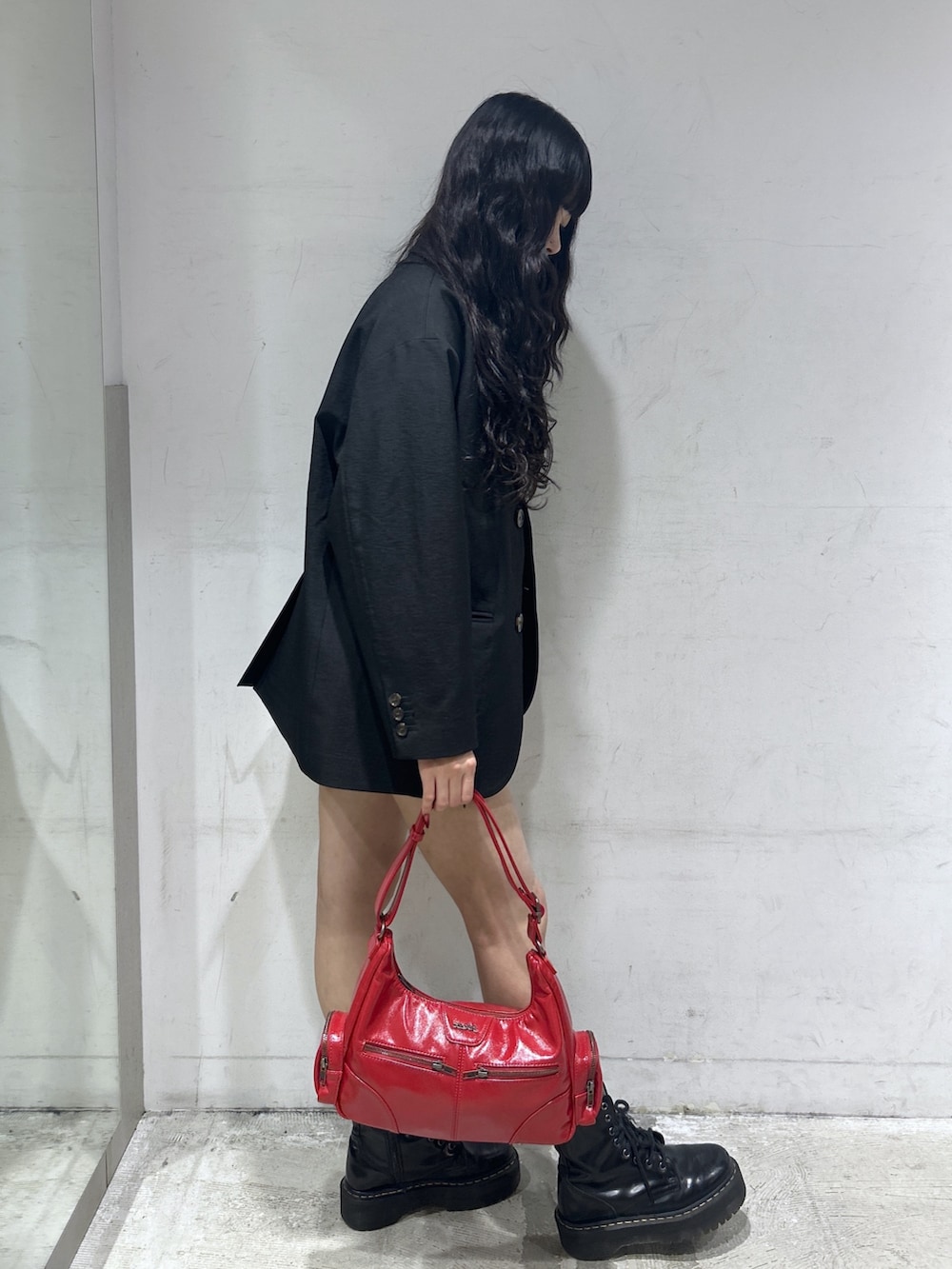 レッド系のショルダーバッグ、ブラック系のテーラードジャケット、ホワイト系のTシャツ/カットソーを着用したレディースの春コーディネートの2枚目の写真
