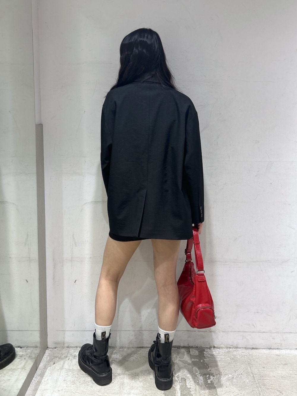 レッド系のショルダーバッグ、ブラック系のテーラードジャケット、ホワイト系のTシャツ/カットソーを着用したレディースの春コーディネートの3枚目の写真