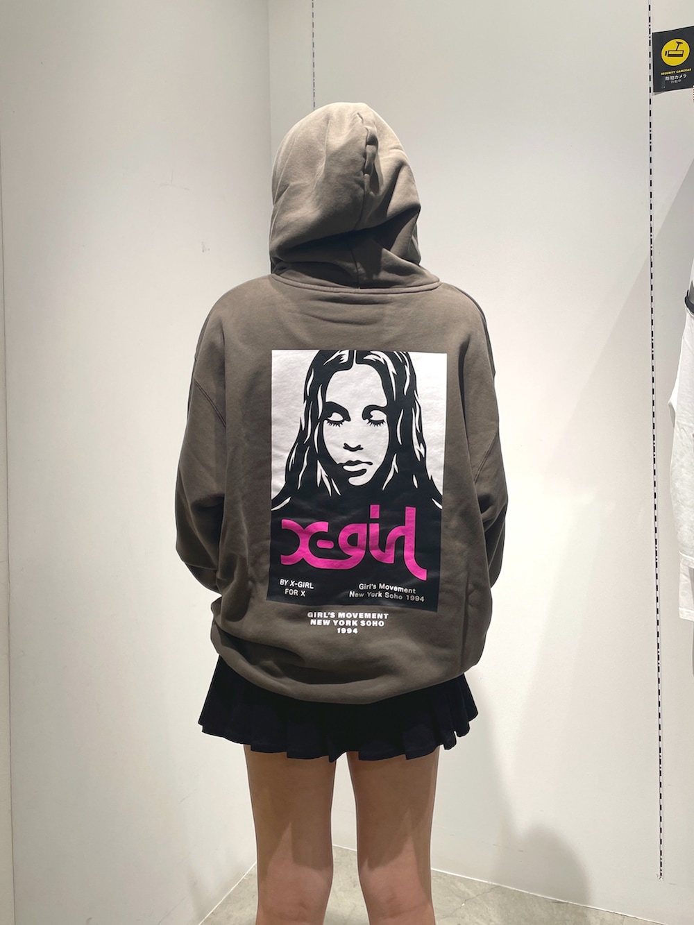 グリーン系のパーカー、ブラック系のスカート、ホワイト系のコインケースを着用したレディースの秋コーディネートの4枚目の写真