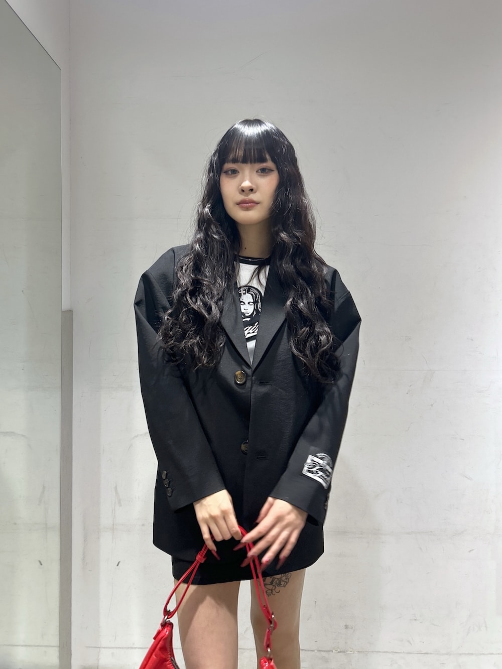 レッド系のショルダーバッグ、ブラック系のテーラードジャケット、ホワイト系のTシャツ/カットソーを着用したレディースの春コーディネートの4枚目の写真