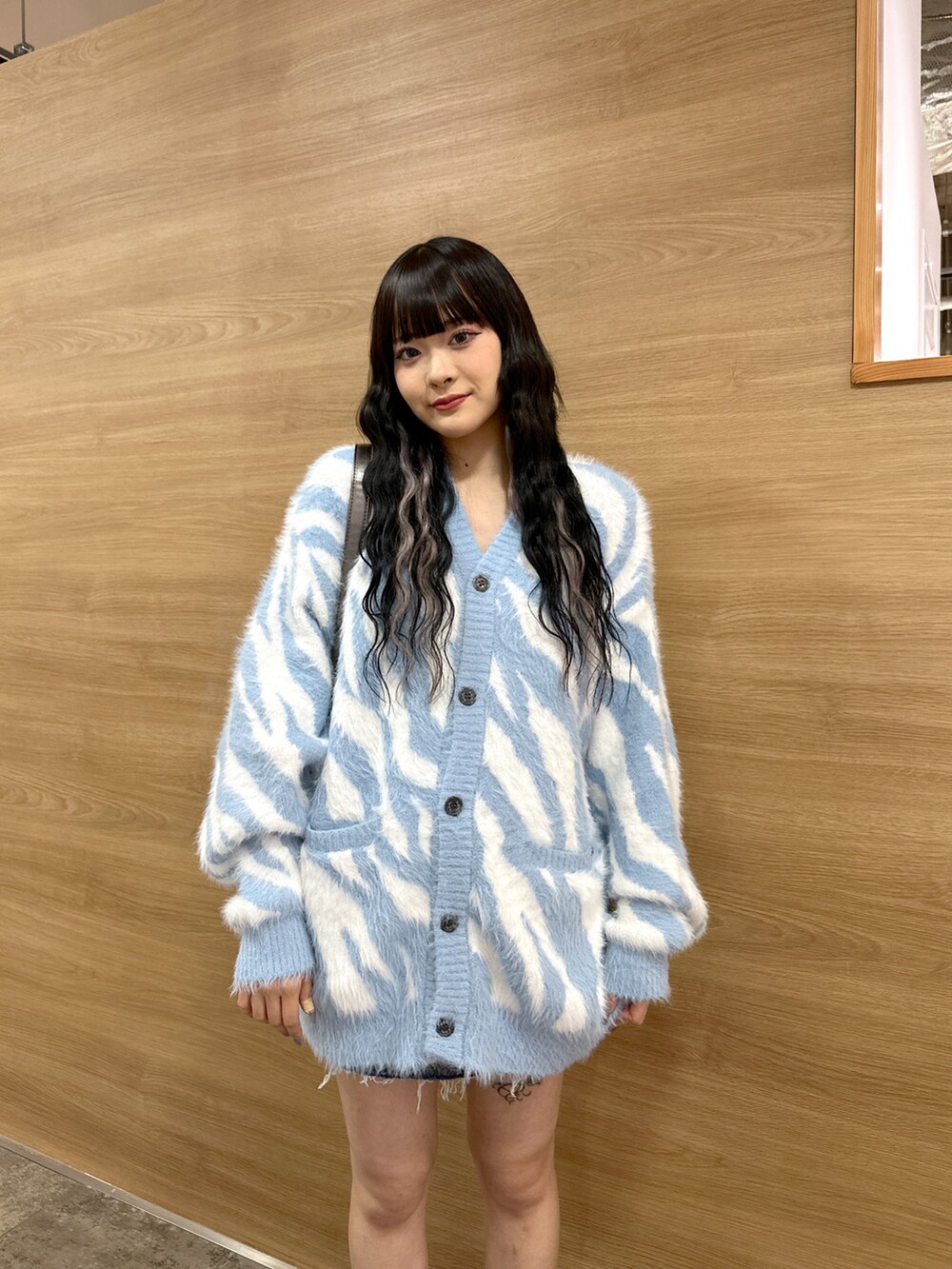 ブルー系のカーディガン/ボレロ、ブルー系のデニムスカート、グレー系のハンドバッグを着用したレディースの秋コーディネートの4枚目の写真